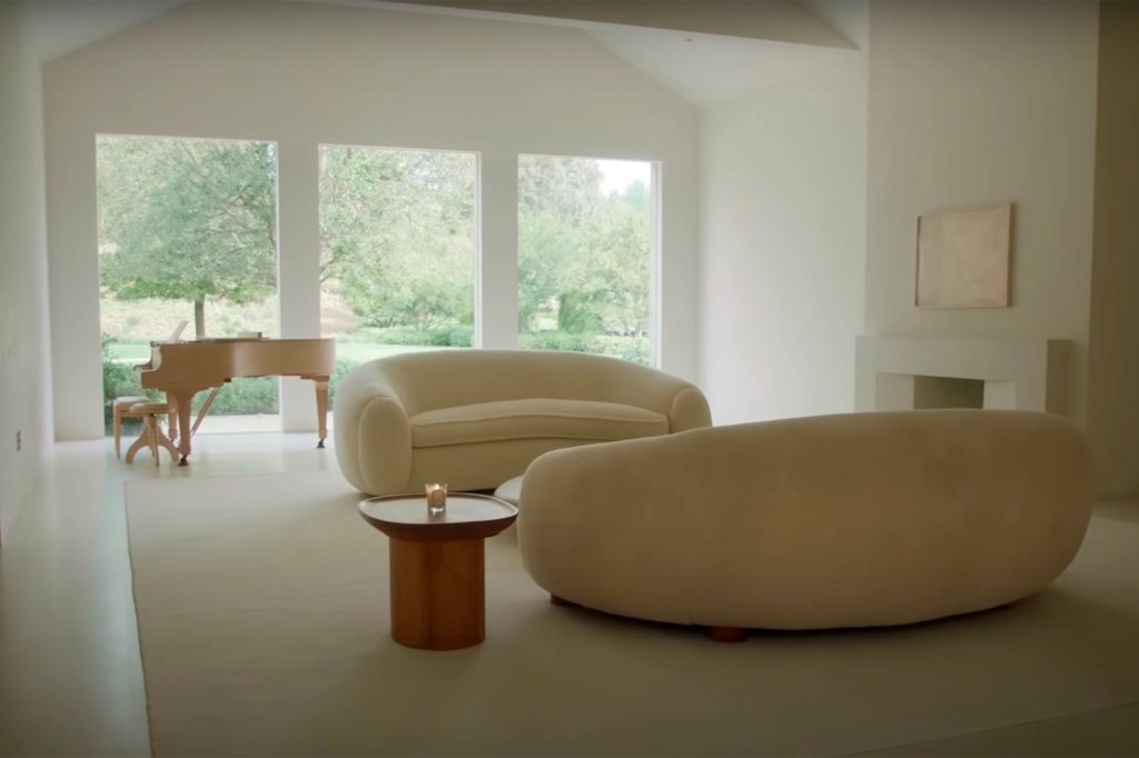 Leggero e arioso: un altro spazio per sedersi in una casa da 23 milioni di dollari dispone di due divani curvi e un pianoforte a coda montato su finestre dal pavimento al soffitto.