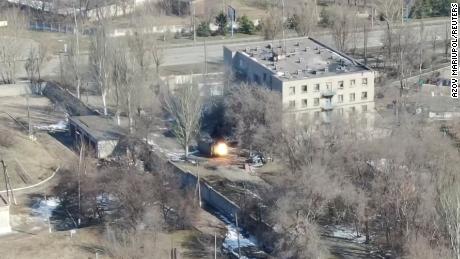 Questo screenshot del filmato del drone mostra un veicolo militare che spara colpi di arma da fuoco vicino a un edificio.