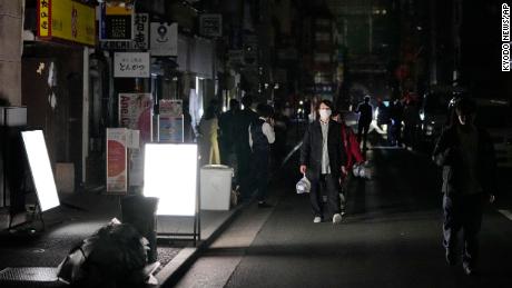 La gente cammina per strada durante un'interruzione di corrente a Tokyo.