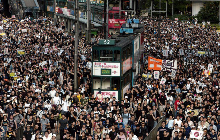 Protesta di massa a Hong Kong nel 2003 per un progetto di legge sulla sicurezza.  C'è un autobus a due piani tra la folla