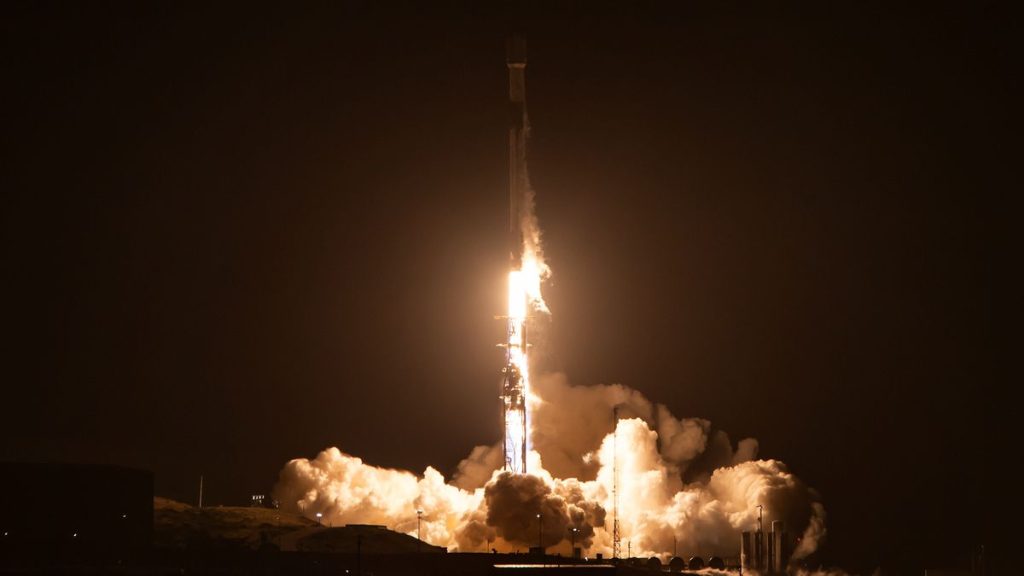 a black-and-white spacex falcon 9 rocket launches into a night sky.
